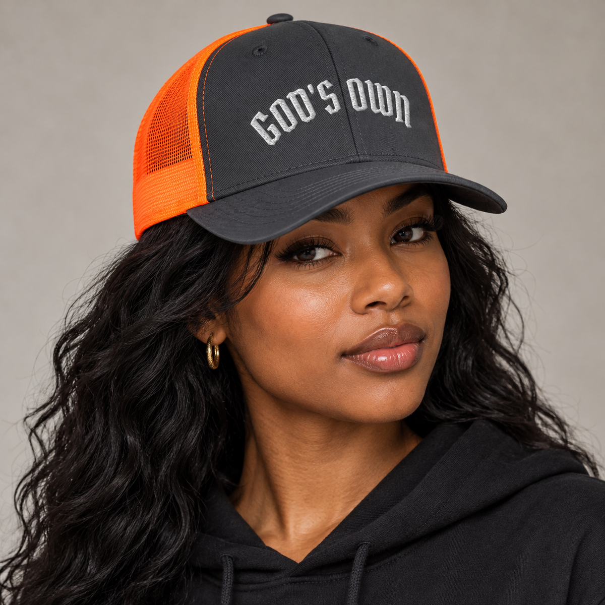 Model mockup of God's Own trucker cap in Charcoal / Neon Orange