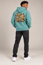 Smiling male model wearing Pigment Alpine Green Jesus hoodie, back artwork visible
